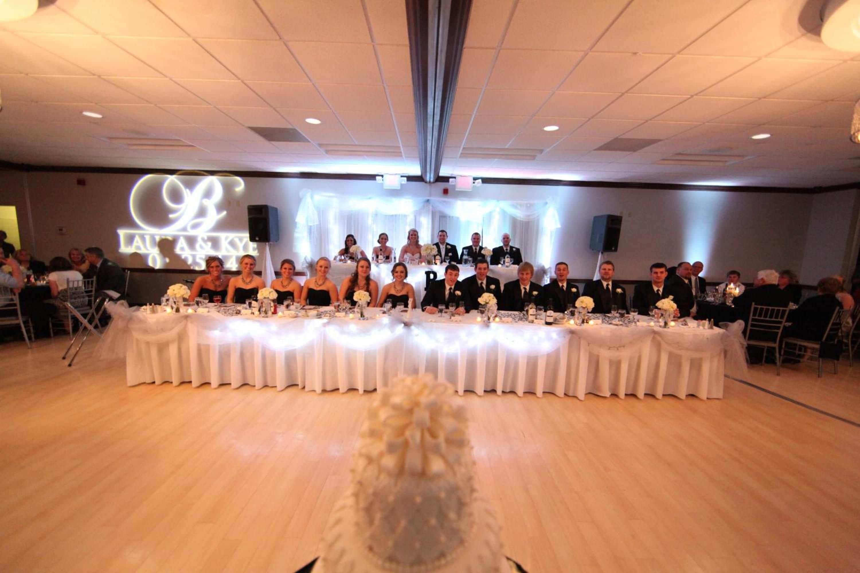 A banquet hall with a long table set for a formal event, flanked by rows of chairs.