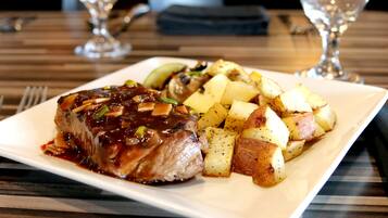 A plate of food with a glazed meat and roasted potatoes on a rectangular white plate.