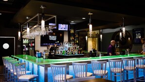 A bar area with a green bar counter, multiple hanging chandeliers, and bar stools. - Unique Suites Hotel (Charleston)