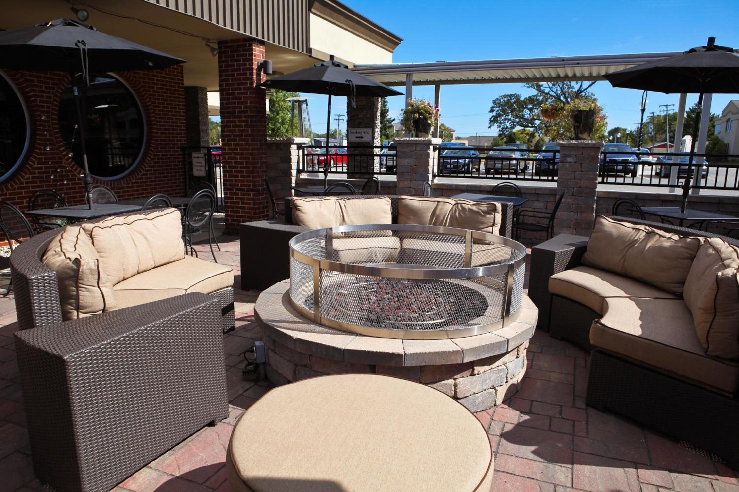 An outdoor seating area with wicker furniture, a round table, and a fire pit.