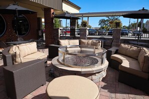 An outdoor seating area with wicker furniture, a round table, and a fire pit. - Unique Suites Hotel (Charleston)