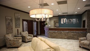 A hotel lobby with a reception desk, patterned armchairs, a beige sofa, and a chandelier. - Unique Suites Hotel (Charleston)