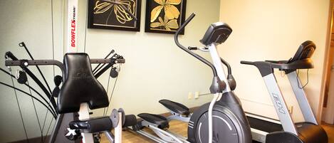 A home gym with stationary bikes, a treadmill, and weight machines.