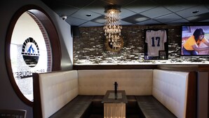 A modern interior with a seating area, a chandelier, and a television screen displaying a person. - Unique Suites Hotel (Charleston)