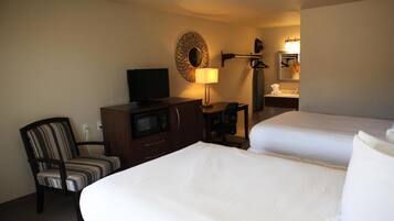 Une chambre d’hôtel avec deux lits, une télévision, un bureau, une lampe et un miroir.
