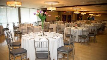 Un salón de banquetes con mesas redondas, sillas y candelabros.