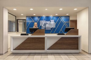 A reception desk with a blue and white geometric design, two computer stations, and a sign for Holiday Inn Express & Suites. - Holiday Inn Express and Suites Indianapolis W- Airport Area by IHG (Indianapolis)