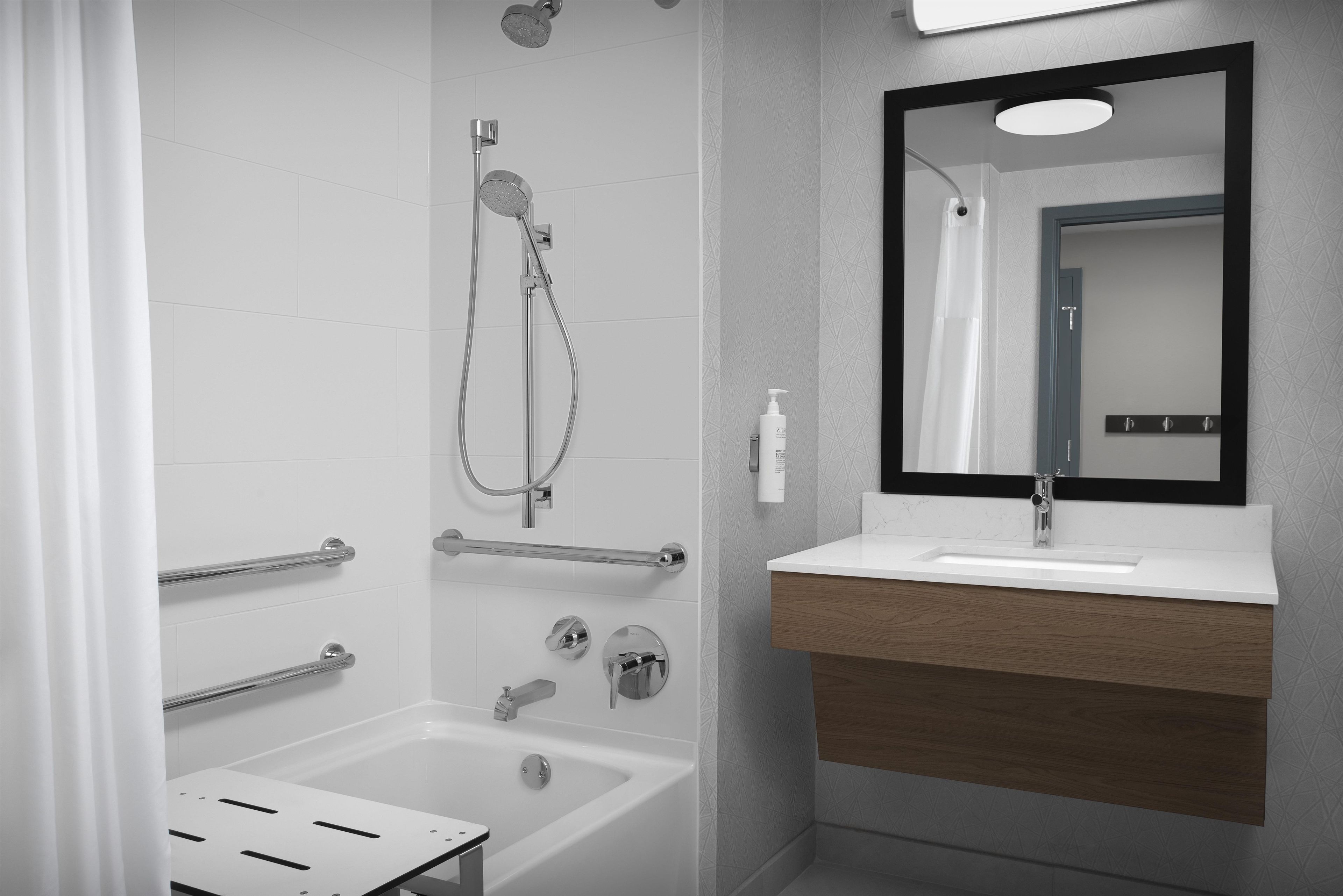 A modern bathroom with a shower, a bathtub, a sink with a mirror, and a towel rack.