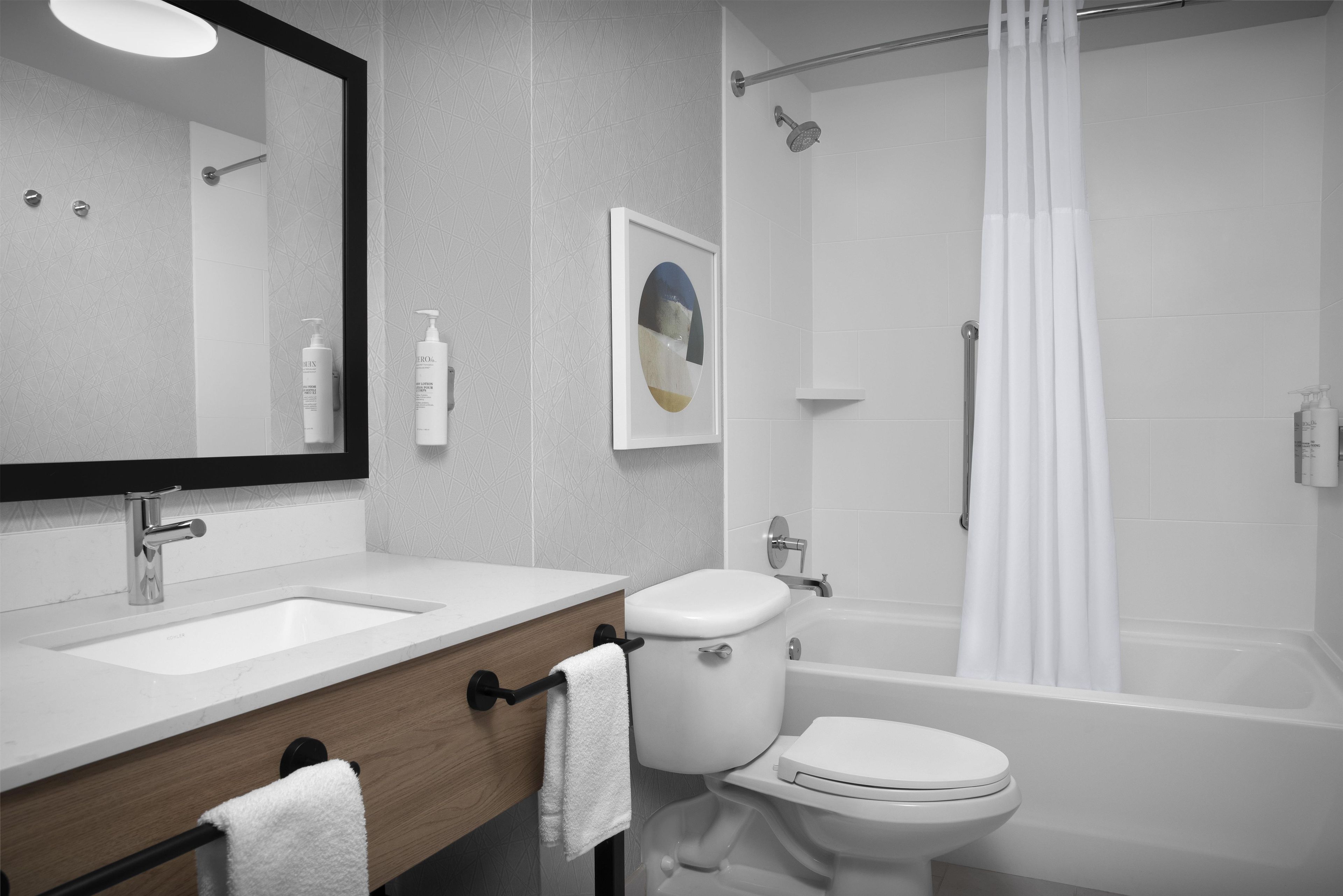 A modern bathroom with a double sink vanity, a toilet, a bathtub, and a shower.