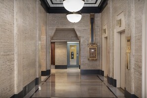 A hallway with a polished floor, a modern light fixture, a door labeled 'Sales Office,' and a wall-mounted elevator control panel. - Hampton Inn Indianapolis Downtown Across from Circle Centre (Indianapolis)