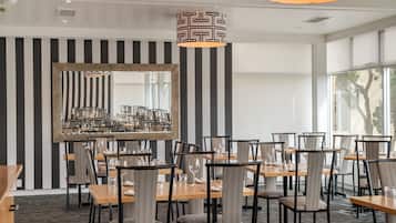 A dining area with striped walls, a large mirror, and modern furniture.