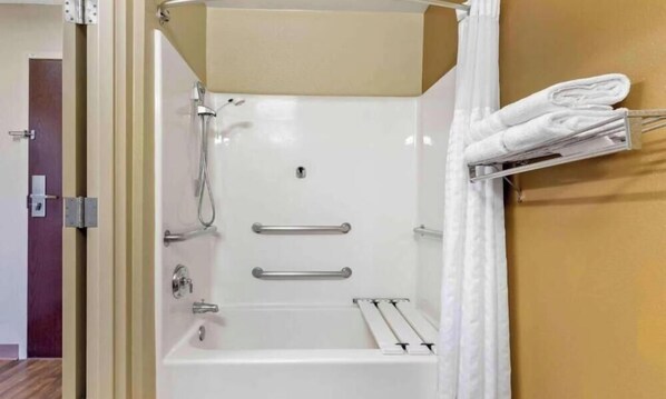 Una ducha sin barreras, una bañera, un perchero y una puerta que da a otra habitación.