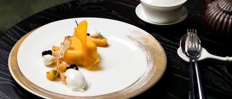 A plate of food with a white bowl and teapot on a table.