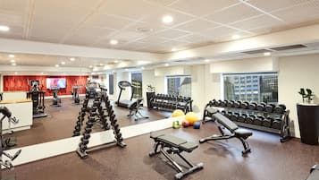 A modern gym with various exercise equipment, including treadmills, dumbbells, and weight machines.