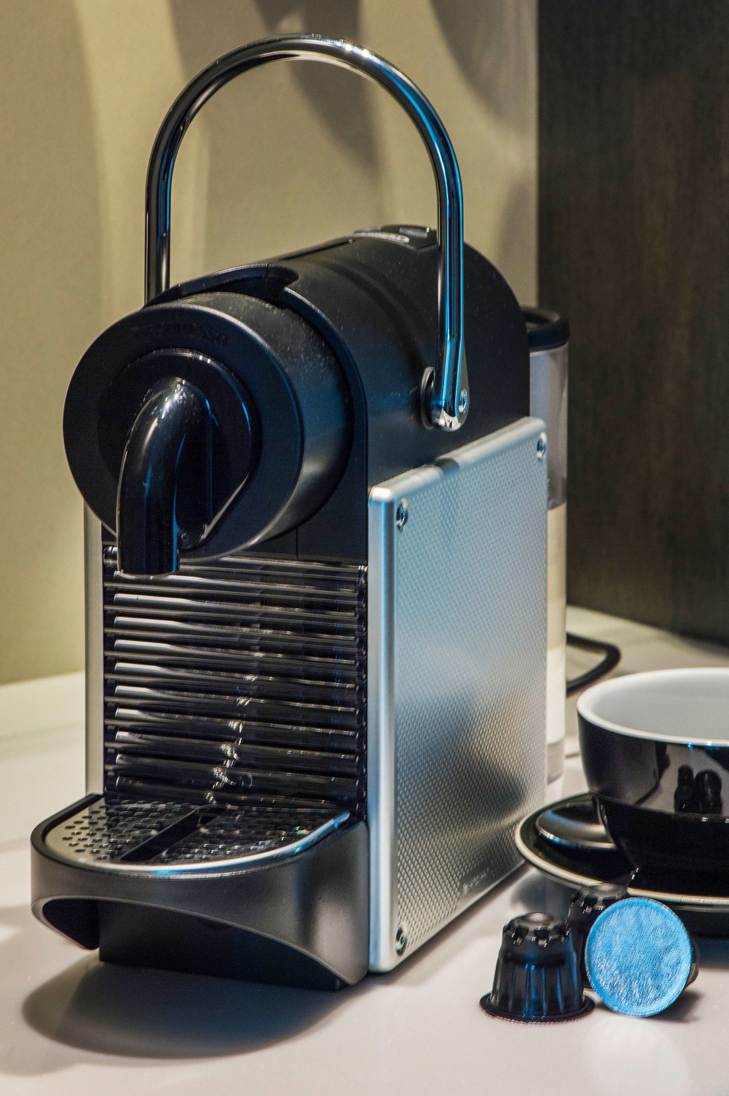 A coffee machine with a handle, a control panel, and a cup holder.