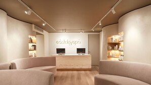 A spa reception area with a modern design, featuring a reception desk, two televisions, and a light wood floor. - SkyCity Hotel (Auckland)