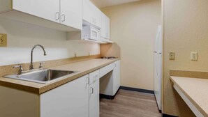 A compact kitchen with white cabinets, a stainless steel sink, a microwave, and a refrigerator. - Extended Stay America Suites Syracuse Dewitt (East Syracuse)