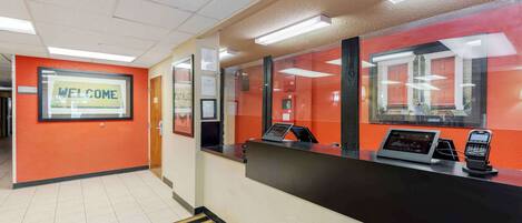 A reception area with a 'WELCOME' sign, a reception desk, a phone, and a window with a view of the building's interior.