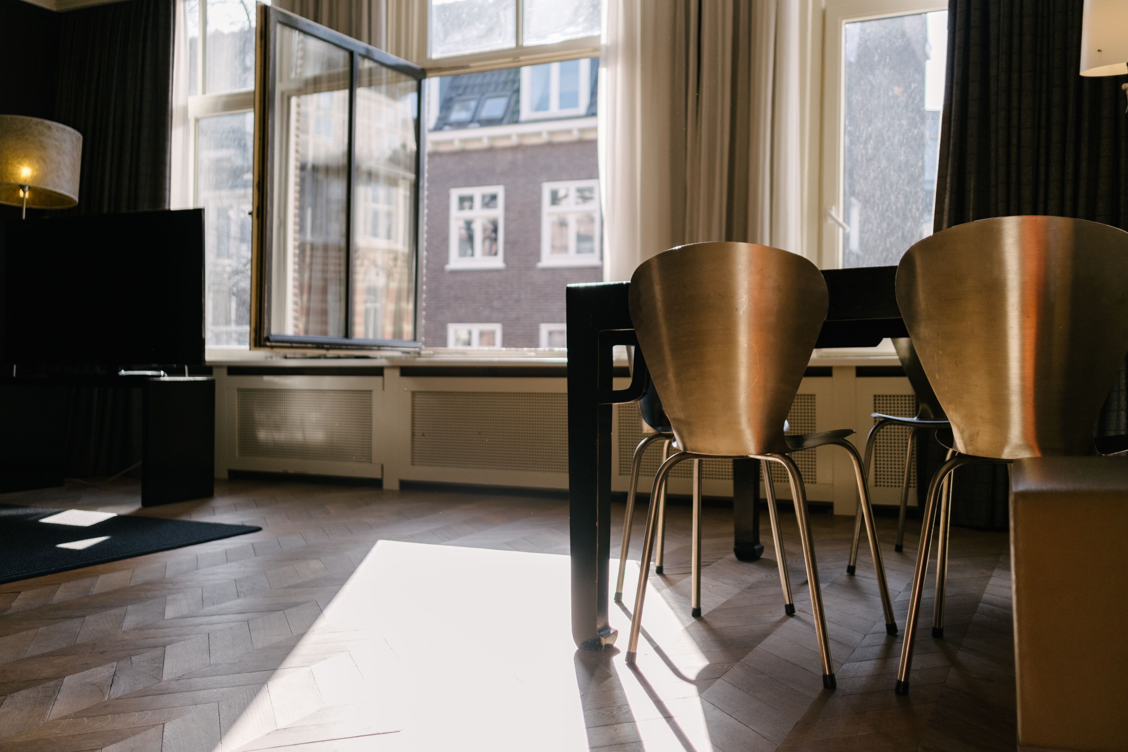 A modern room with a large window, two chairs, a table, and a lamp.