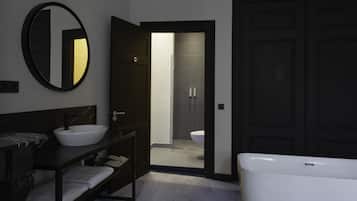 Un baño moderno con una bañera grande, un espejo redondo, un tocador oscuro y una zona de ducha.
