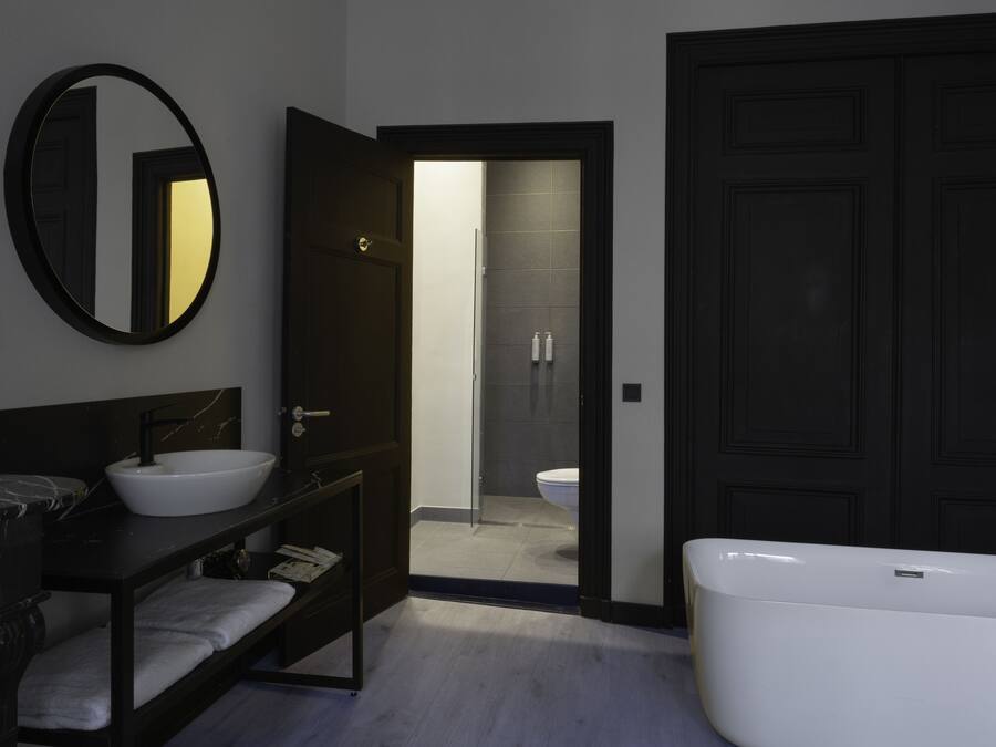 Un baño moderno con una bañera grande, un espejo redondo, un tocador oscuro y una zona de ducha.