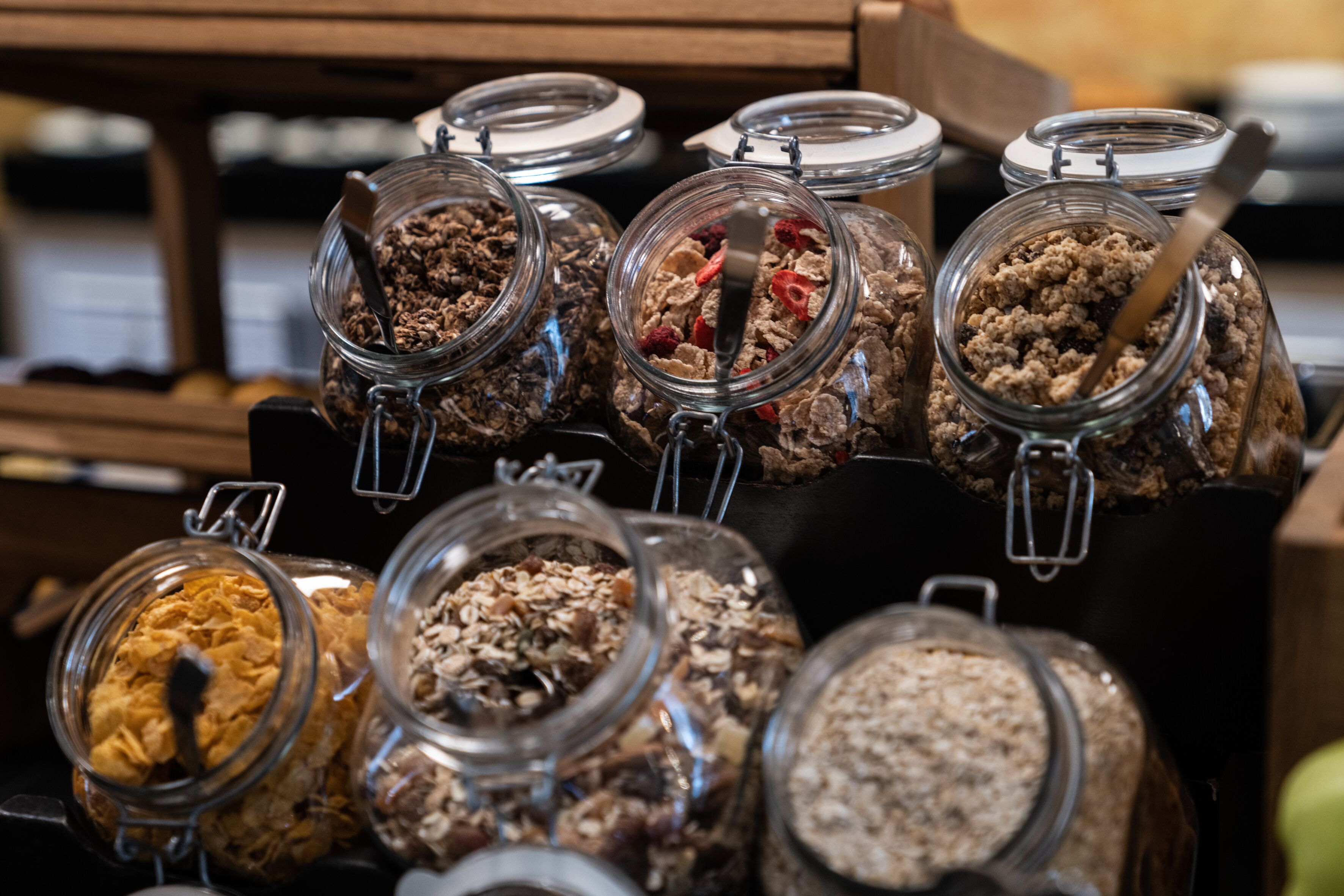 Una exhibición de distintas barras de granola y cereal en frascos de vidrio con cierres metálicos.