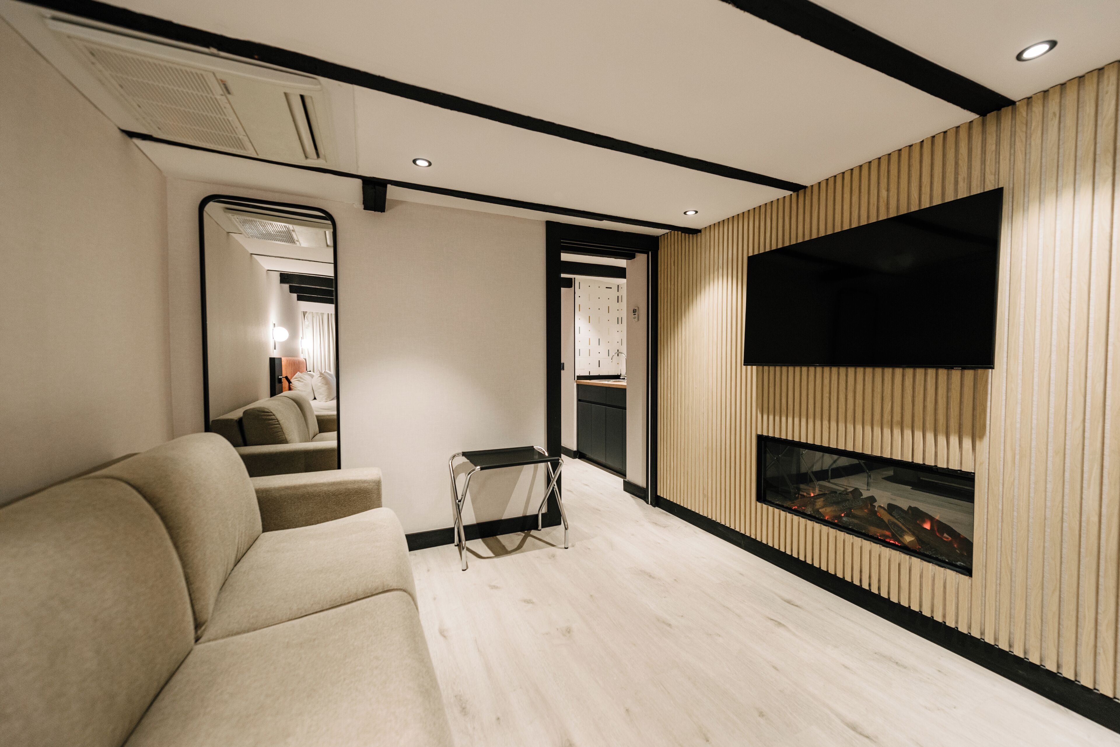 Un salon moderne avec un canapé, une petite table, une cheminée et un téléviseur fixé au mur.