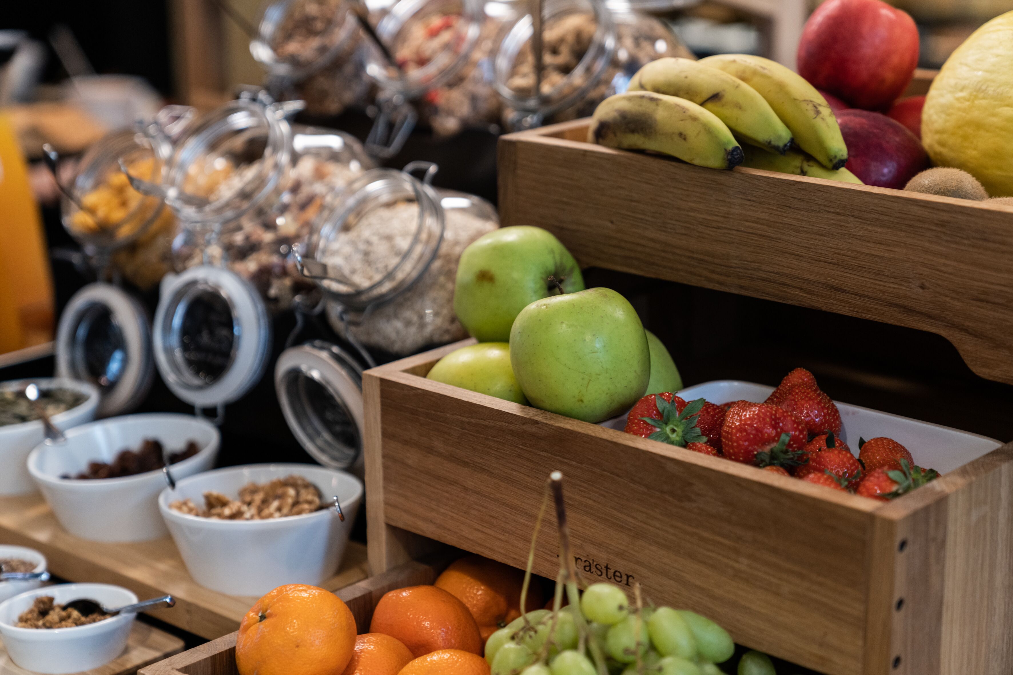 A breakfast buffet with various fruits, nuts, and granola.