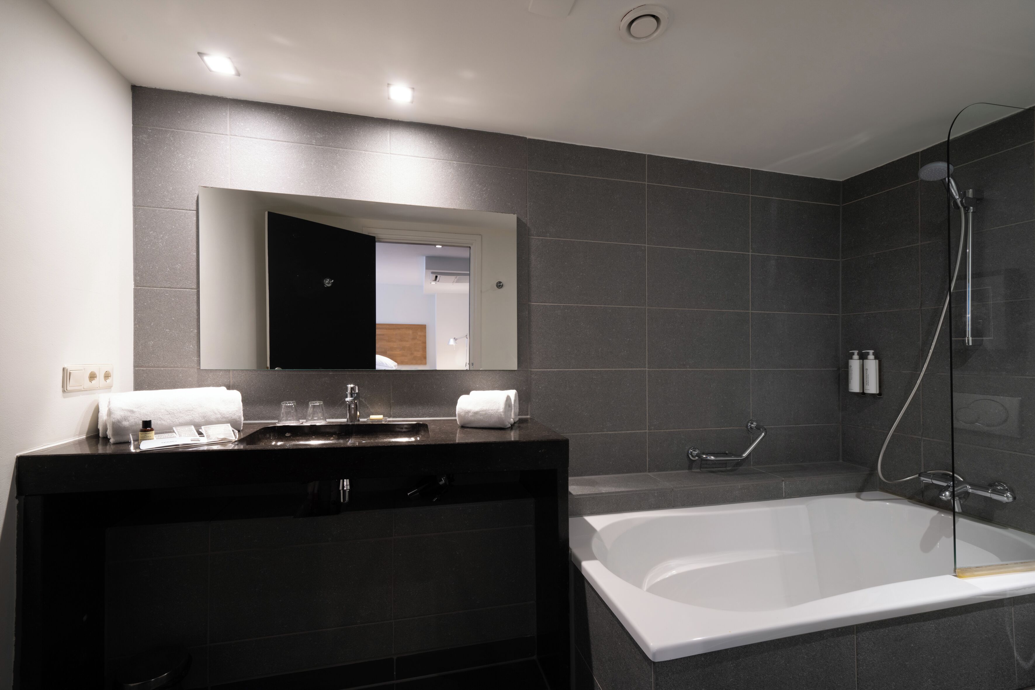 A modern bathroom with a large bathtub, a dark vanity with a mirror, and a shower area.