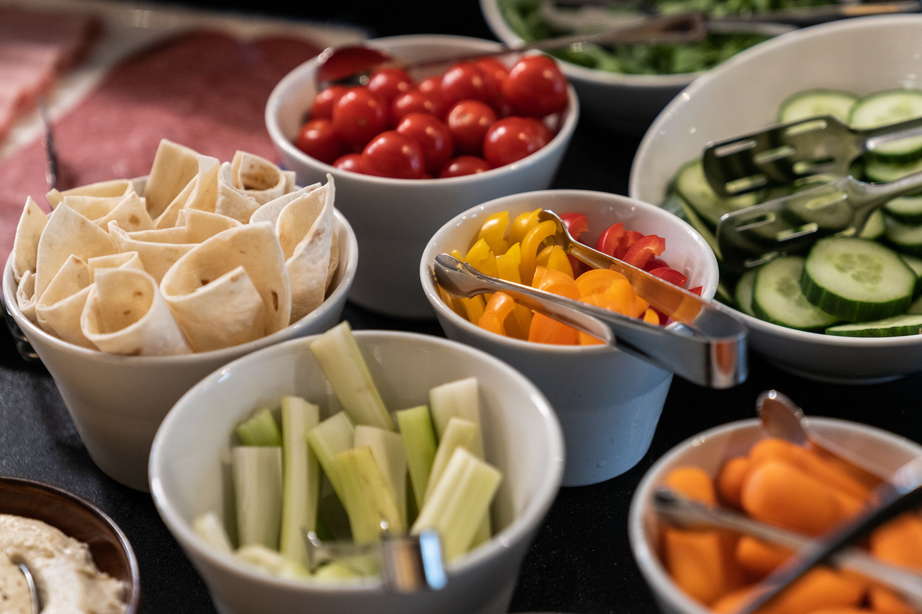 A variety of food items including tortillas, cherry tomatoes, bell peppers, celery, cucumbers, and carrots.