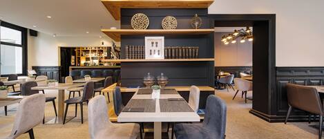 Un comedor moderno con una mesa central rodeada de sillas, una zona de bar con estantes y vistas al exterior.