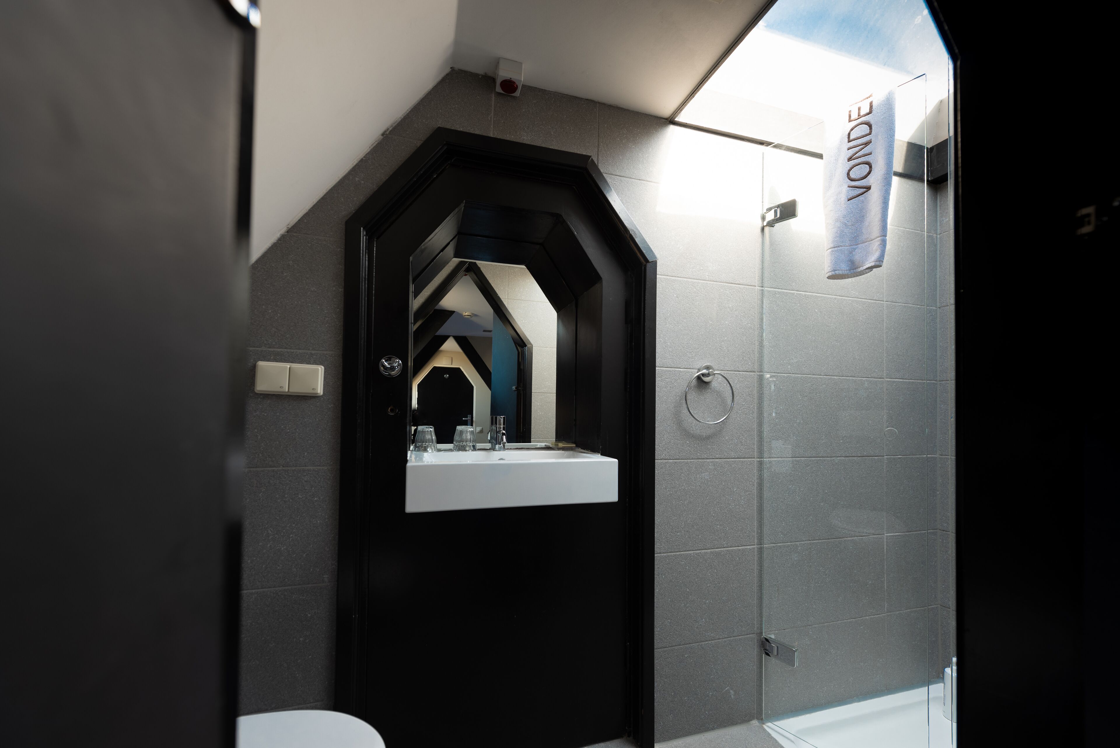 Un baño moderno con un tocador negro, un lavamanos blanco y una toalla colgada en la pared.