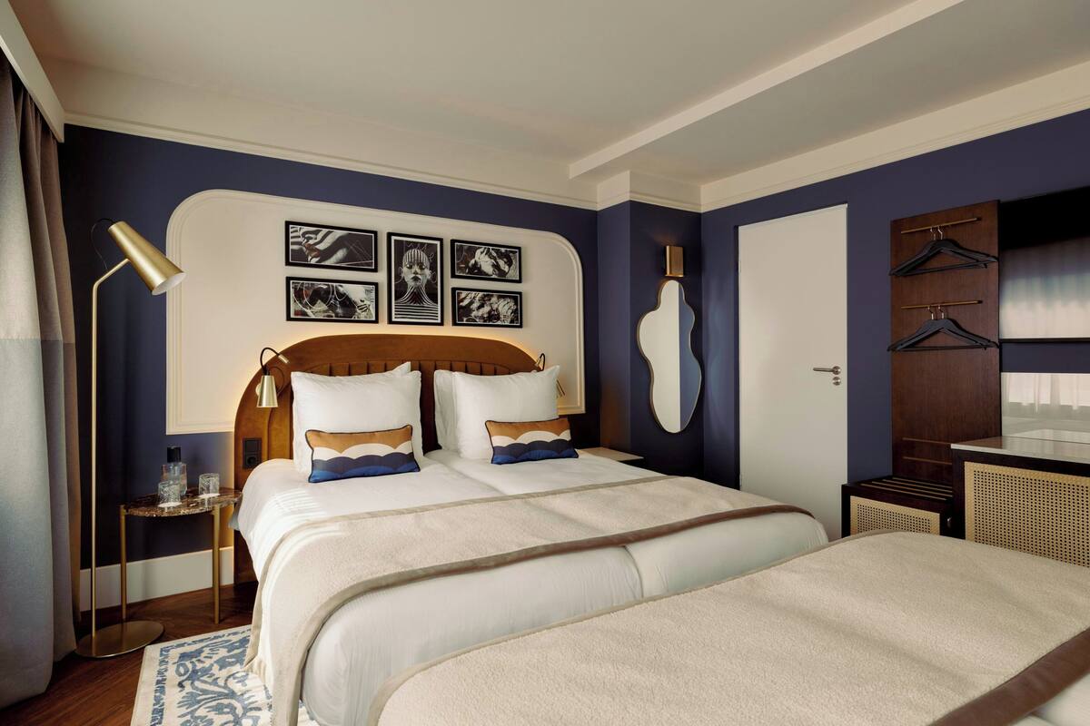 A hotel room with a large bed, bedside tables, a mirror, and artwork on the wall.