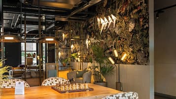 Un ambiente acogedor en el interior, con una mesa de madera, un tablero de ajedrez y sillas estampadas.