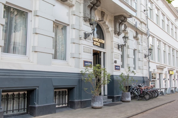 A building with a sign reading "Lancaster Hotel" and a row of bicycles parked outside.
