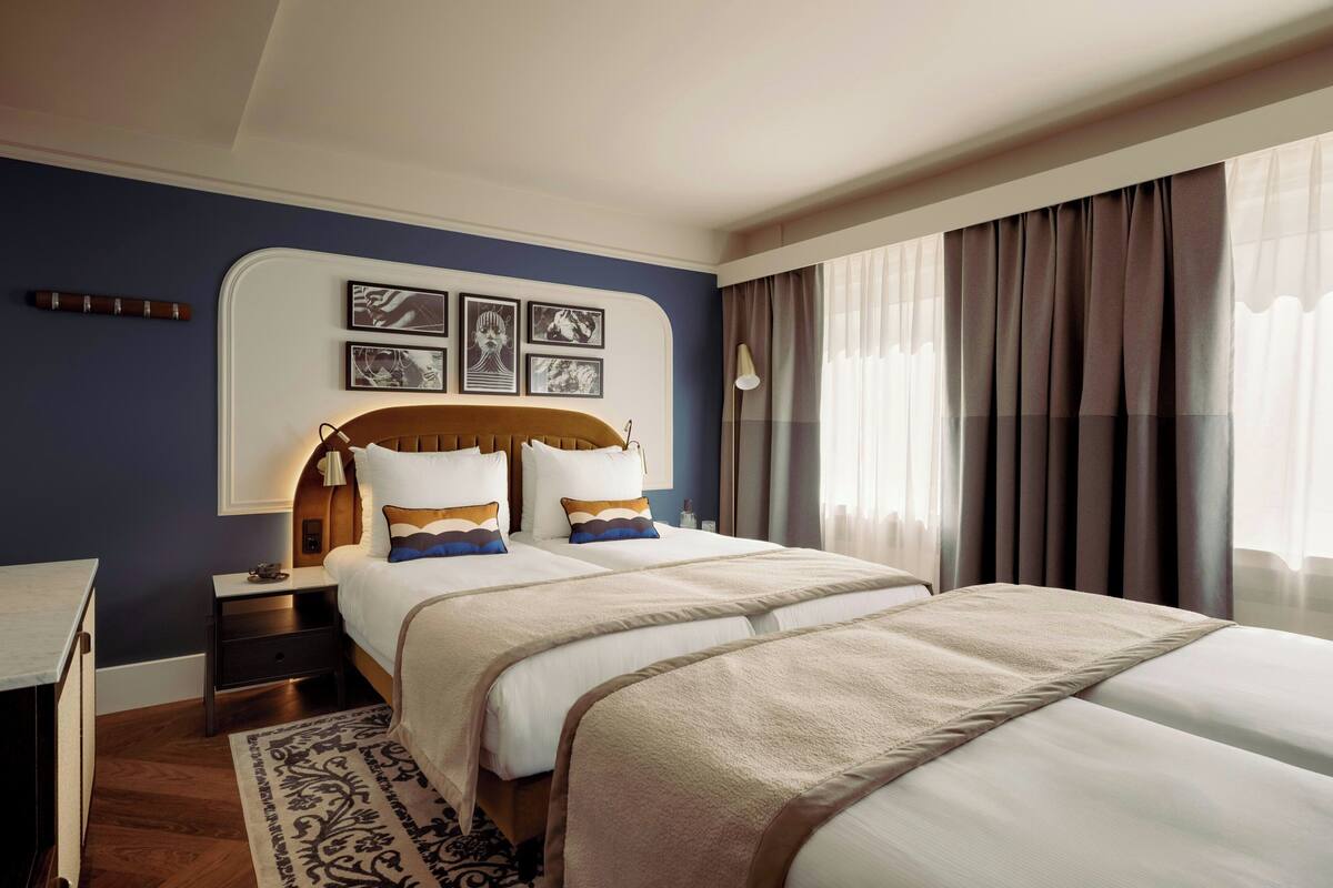 A double bed with a wooden headboard, a bedside table, a lamp, and a wall-mounted artwork.