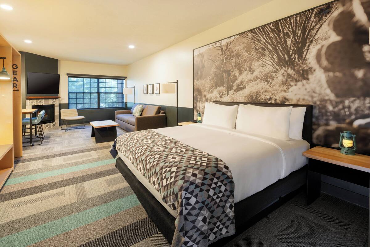 Une chambre d’hôtel avec un grand lit, une télévision, un canapé, un bureau et une grande œuvre d’art murale.