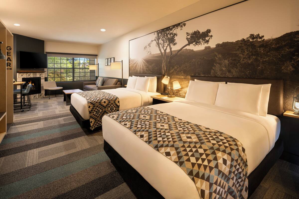 Une chambre d’hôtel avec deux lits, un téléviseur à écran plat, une cheminée, un bureau et une grande fenêtre.