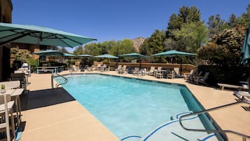 Una piscina al aire libre, sombrillas, sillones reclinables de piscina