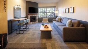 A modern living room with a fireplace, a sofa, a coffee table, and a TV mounted on the wall. - Mountain Modern Sedona, Tapestry Collection by Hilton (Sedona)