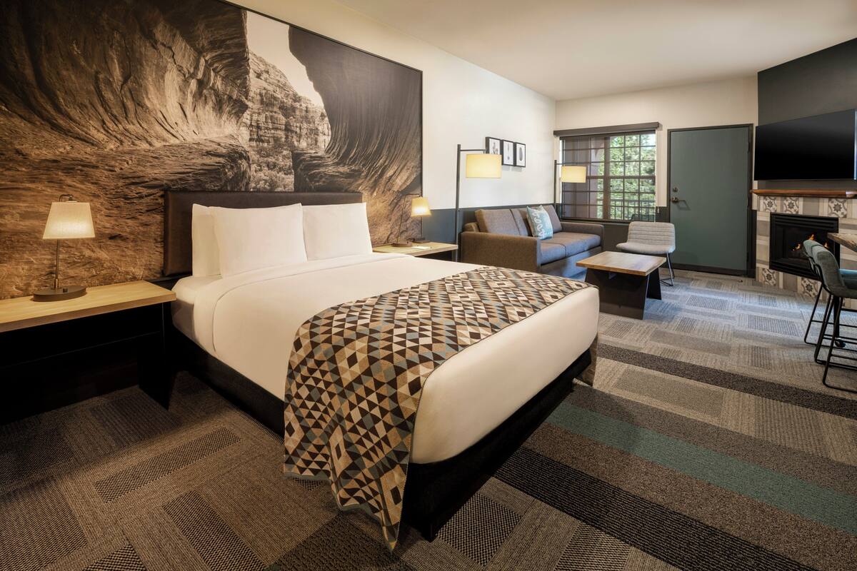 Une chambre d’hôtel avec un grand lit, un canapé, une télévision et une cheminée.