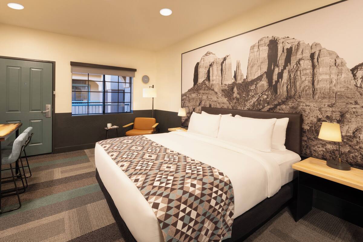 Une chambre d’hôtel avec un grand lit, un bureau, une chaise et une fenêtre.