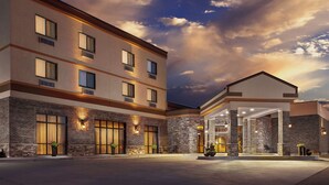 Un hotel de varios pisos con fachada de ladrillo, ventanas amplias y un área de entrada cubierta.