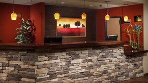 Zona de recepción con pared de piedra, mostrador de madera e iluminación colgante.
