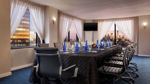 A conference room with a long table, chairs, and a city view.