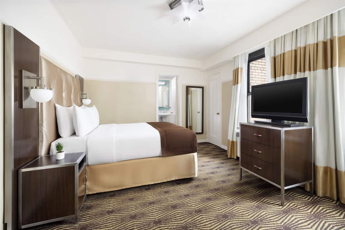 A hotel room with a bed, a TV, a dresser, and a nightstand.