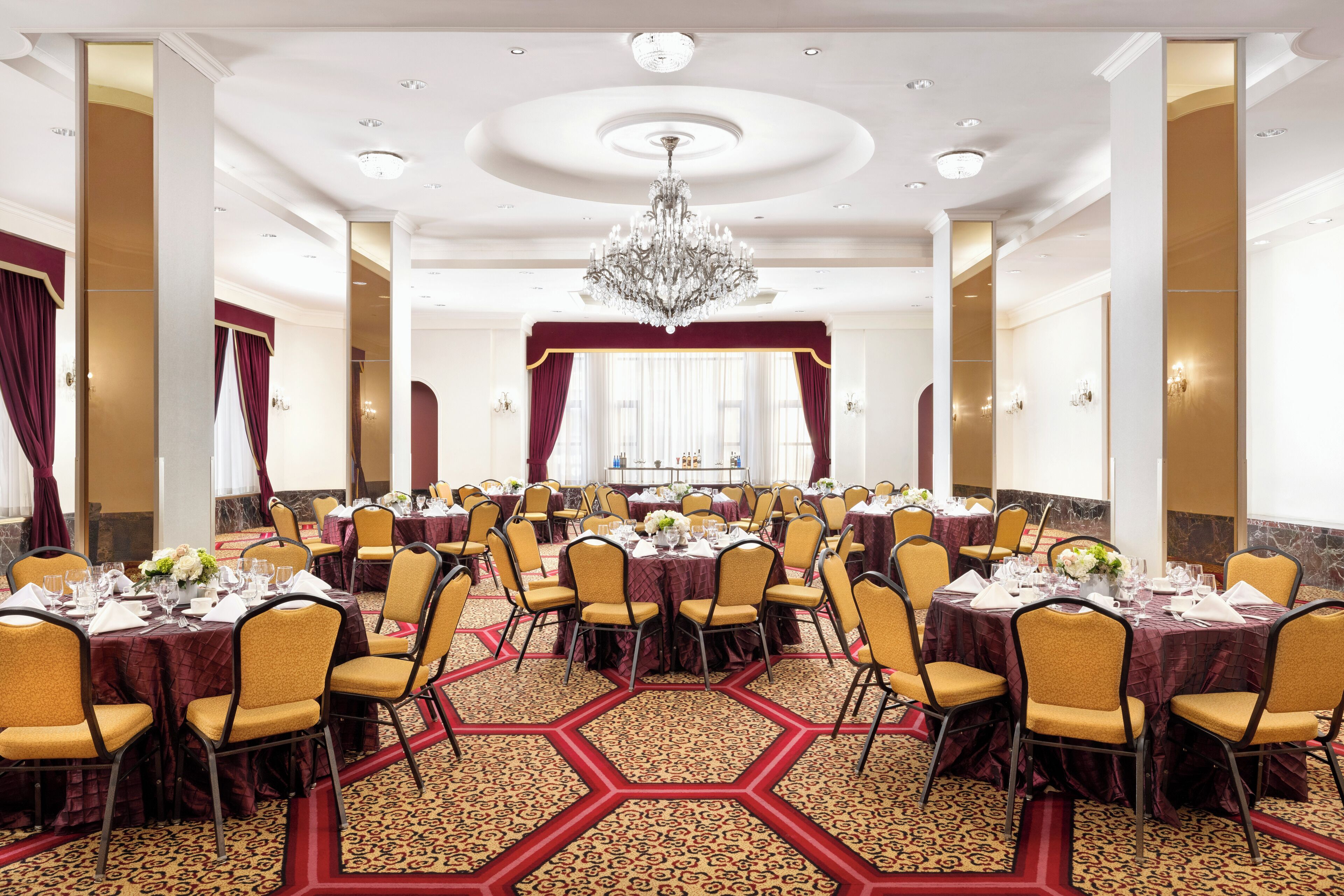 Une salle de banquet avec des tables rondes, des chaises et un lustre.