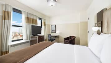 Une chambre d’hôtel avec un grand lit, un bureau avec une chaise, une télévision et une fenêtre avec des rideaux.