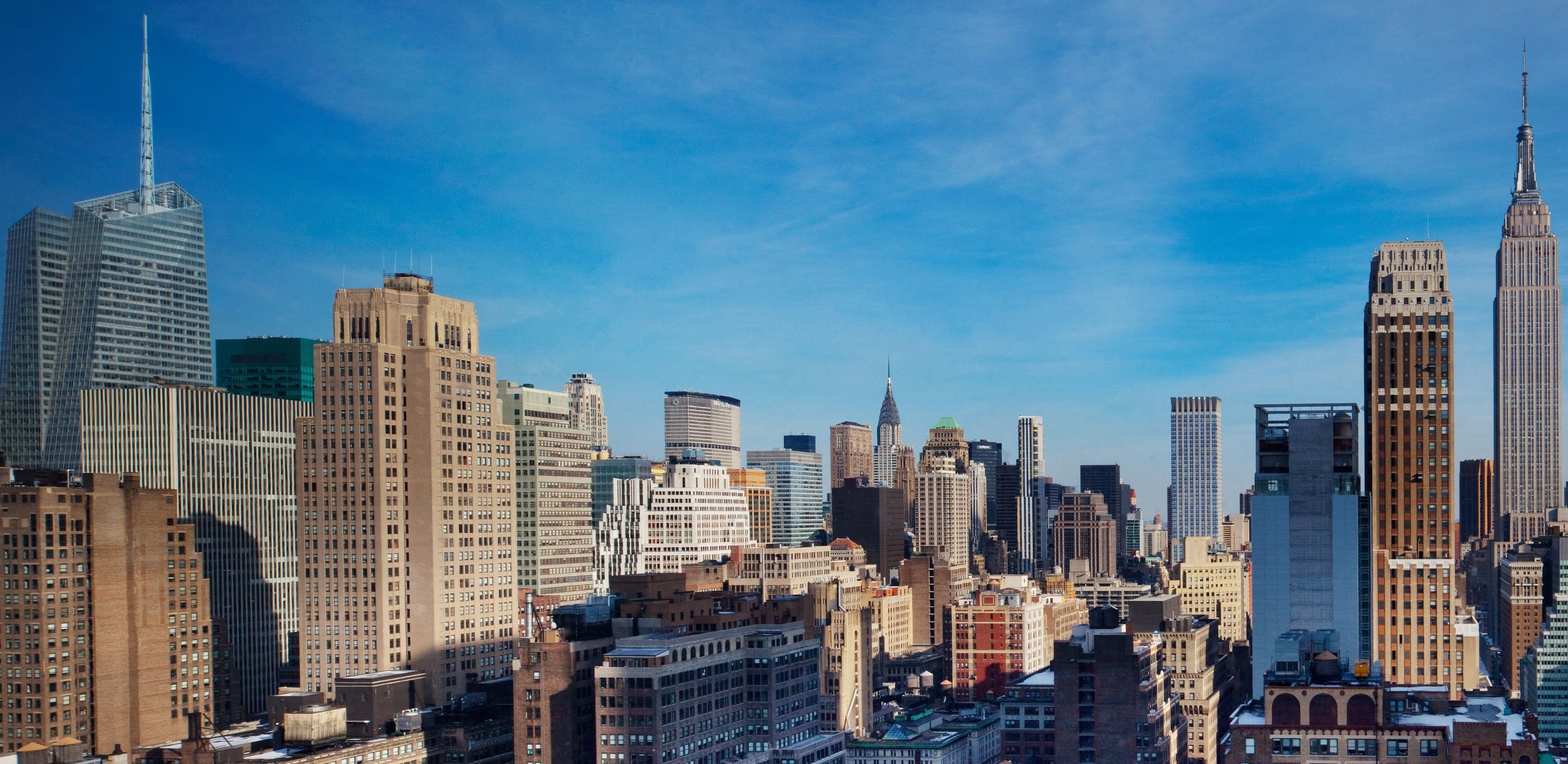 A cityscape with a variety of high-rise buildings, including a prominent skyscraper with a spire.