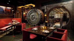 A restaurant with red upholstered booths, a large clock, and a view of the dining area. - NEW YORKER BY LOTTE HOTELS (New York)